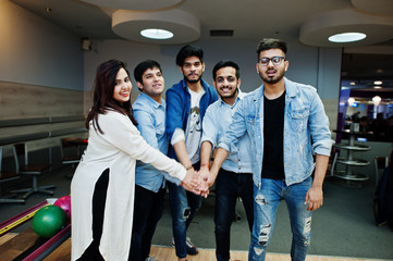 Group of five south asian peoples having rest and fun at bowling club. Putting their hands together, friends showing unity and teamwork.