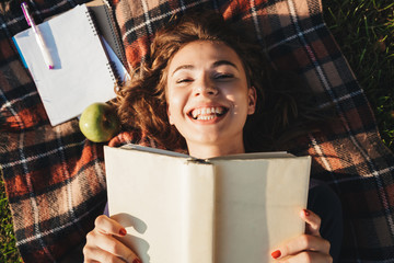 Canvas Print - Cheerful teenage girl laying on a blanket at the park