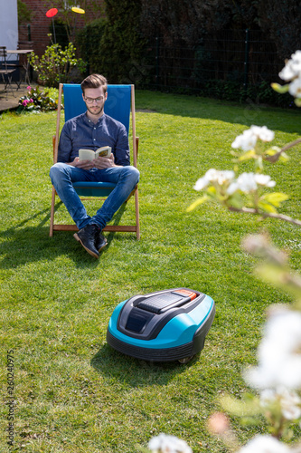 Person Im Liegestuhl Neben Mahroboter Im Garten Buy This Stock
