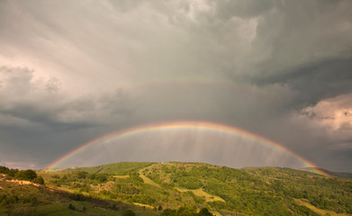 Wall Mural - Beautiful mountain valley with green hills and huge rainbow