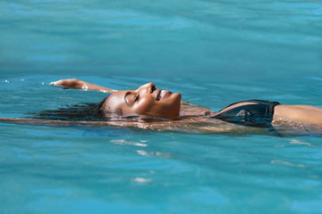 Wall Mural - Relaxed woman floating in swimming pool