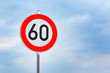 © Firn - Red round 60km/h speed limit sign on highway in front of blue sky