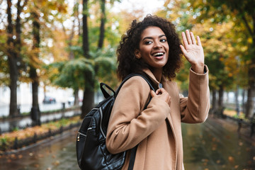 Wall Mural - Beautiful young african woman wearing coat walking outdoors