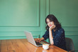 © makistock - Beautiful cute asian young businesswoman in the cafe, using laptop and drinking coffee smiling