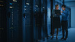 © Gorodenkoff - In the Modern Data Center: Engineer and IT Specialist Work with Server Racks, Talking, Doing System Maintenance Check with Laptop Computer. Concept of Diagnostics of the Database, Cybersecurity Check