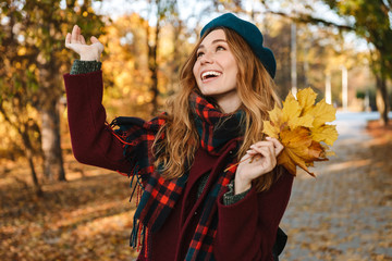 Wall Mural - Cheerful young girl with long brown hair wearing autumn