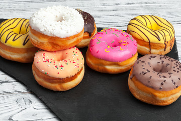 Poster - Several fresh donuts in a black ceramic plate on a wooden table with copy space