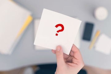 Wall Mural - Woman clerk sitting at the office table and holding note sticker with question mark. Concept.