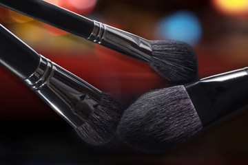 Professional brushes for a make-up close up, against a dark background.