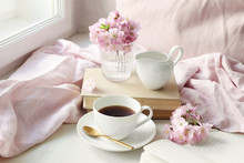 Spring Still Life Scene. Cup Of Coffee, Old Books And Milk Pitcher. Vintage Feminine Styled Photo. Floral Composition With Pink Sakura, Cherry Tree Blossoms On White Table.