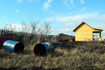  Unfinished country house on a plot of land. Iron water barrel.Wooden fence.