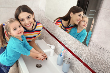 Wall Mural - Happy mother and daughter washing hands in bathroom at home