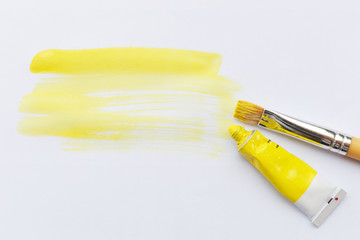 Yellow paint brush color and color tube on white paper background