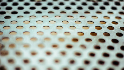 Wall Mural - Closeup perforated aluminium sheet of metal texture. Surface with depth of field, industrial mesh background.