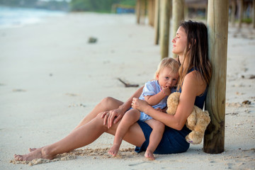 Canvas Print - Happy beautiful fashion family, mom and baby, hugging, casually dressed, enjoying the sunrise on the beach in Mauritius