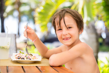 Sticker - Sweet preschool boy, eating fresh salad in a restaurant on beach summer resort