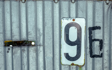 Wall Mural - White Shabby Metal Plate With Black Nuber Nine and Six Nailed On Corrugated Old Iron Sheet