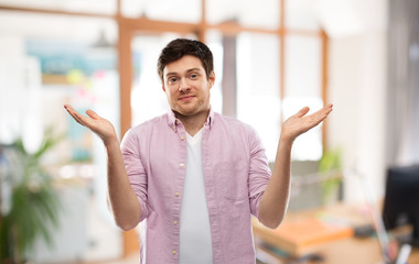 people, emotion and expression concept - young man shrugging over office room background