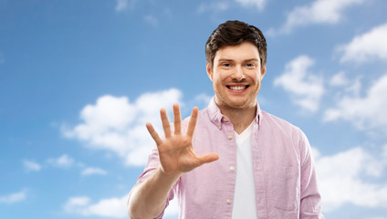 Wall Mural - count and people concept - smiling young man showing five fingers over blue sky and clouds background