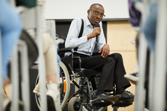 serious confident motivational disabled mature african-american speaker in glasses sitting in wheelc