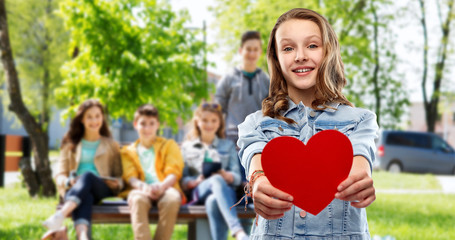 Canvas Print - valentine's day, love and people concept - smiling pretty teenage girl in denim jacket holding red heart over group of friends outdoors background