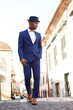 © mimagephotos - Full body african american male model in vintage suit and hat walking in city