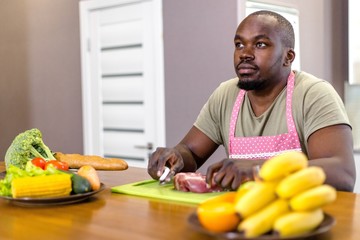 African man cooking meat on the kitchen table