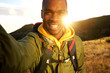 © mimagephotos - happy black man hiking and taking selfie with sunset in background