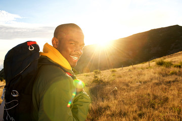 Wall Mural - Close up side of happy man hiking in mountains with backpack