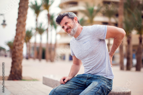 Cuadros en Lienzo Man with back pain sitting on bench at the outdoor