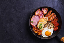 Full English Or Irish Breakfast With Sausages, Bacon, Eggs, Tomatoes, Mushrooms And Beans On Black Background. Room For Text