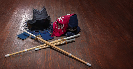 Kendo gloves, helmet and bamboo sword on a wooden surface.