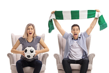 Canvas Print - Soccer fans with a football and a scarf sitting in armchairs and cheering