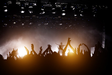 Concert hall with a lit stage and people silhouettes during a concert