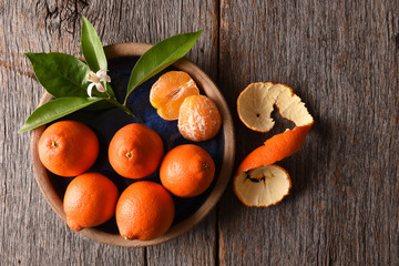 Closeup of peeled fruit on a plate with leaves and orange blossom on a rustic wood table