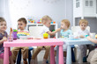 © Oksana Kuzmina - Kids group have lunch in kindergarten. Cute child boy sharing a meal little girl
