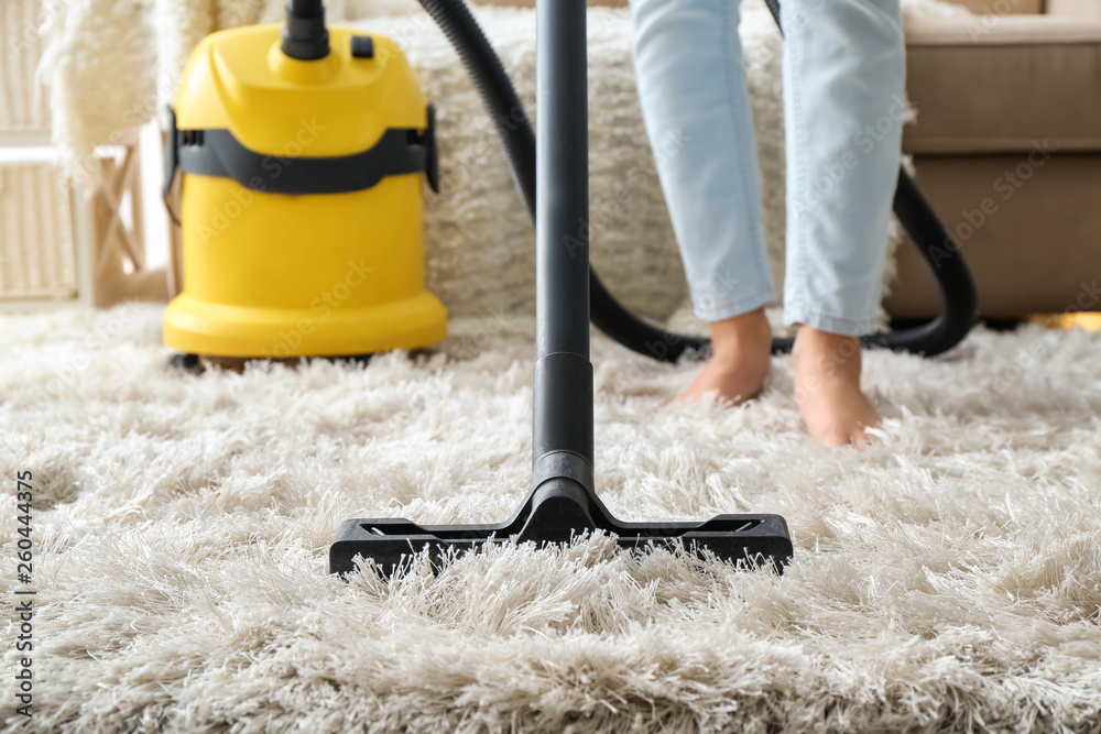 Woman hoovering carpet with vacuum cleaner