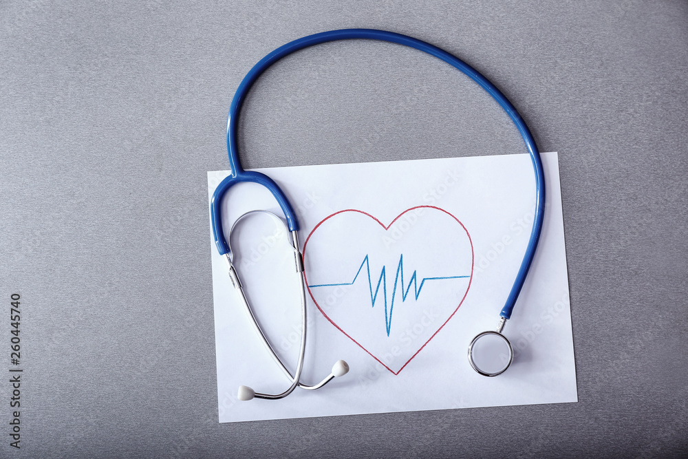 Stethoscope with cardiogram on grey background