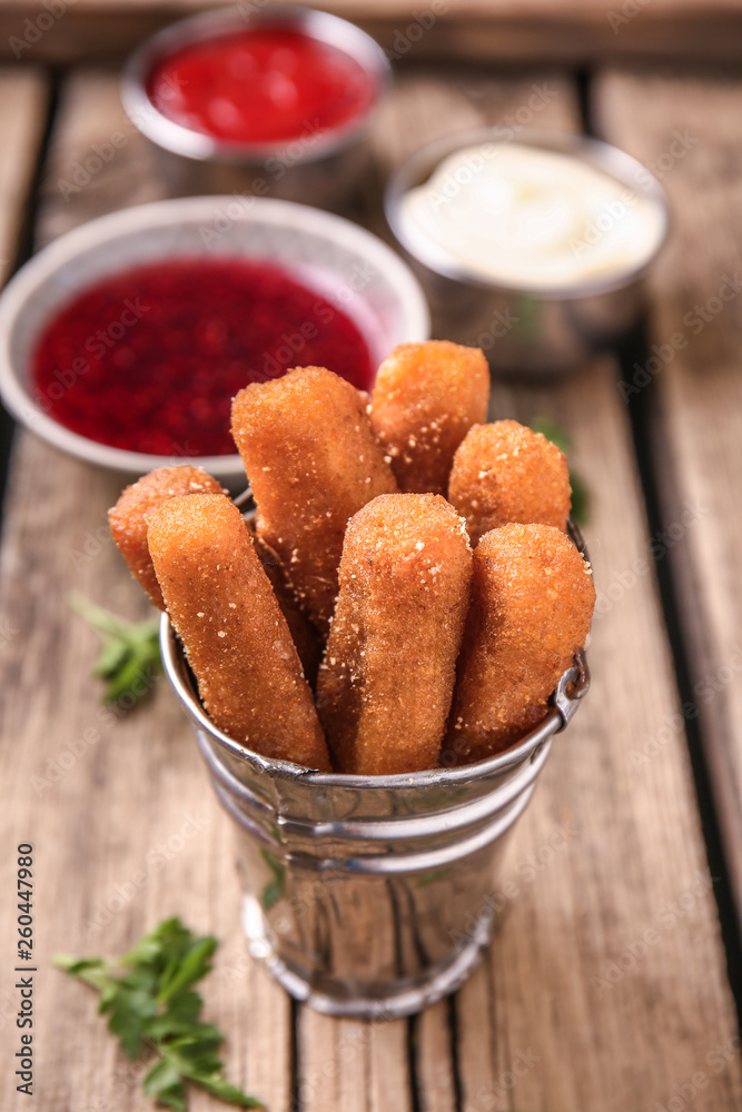 Tasty mozzarella sticks on wooden table
