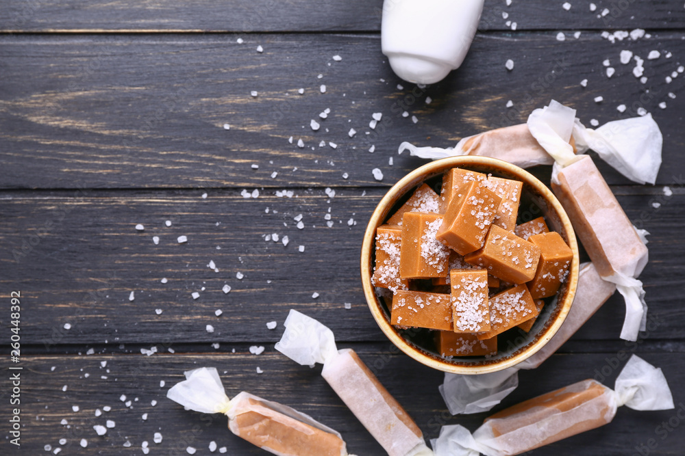 Bowl with tasty salted candies on wooden table