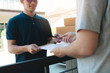 © wutzkoh - Young asian man smiling while delivering a cardboard box to the woman holding document to signing signature.