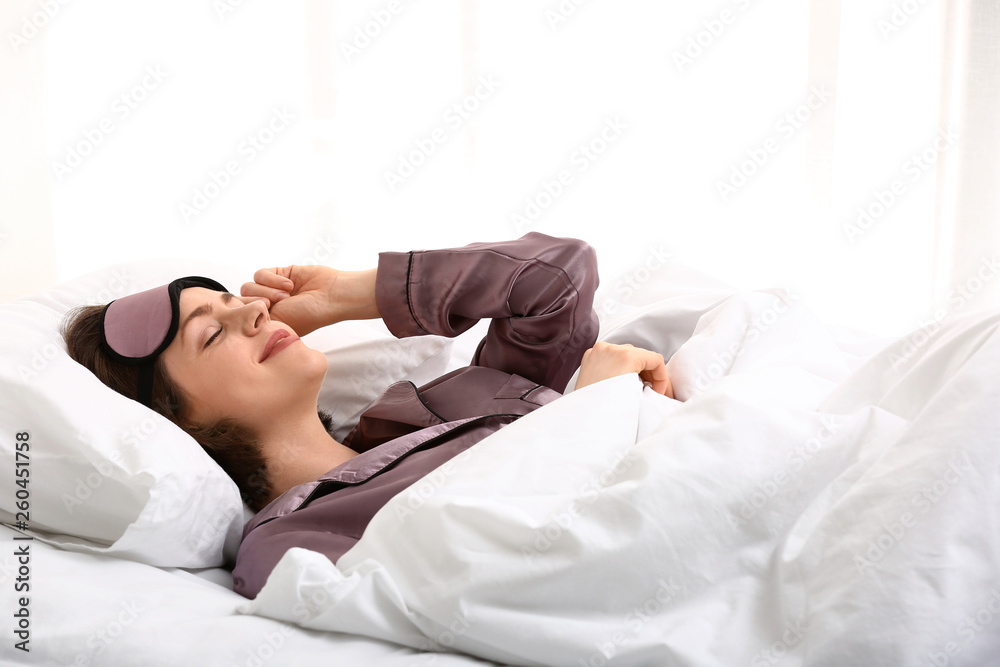 Young woman with sleep mask in bed