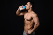 Sporty man with protein shake on dark background
