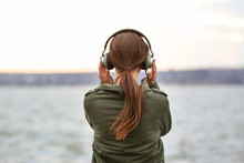 Young Woman Listening To Music Near River