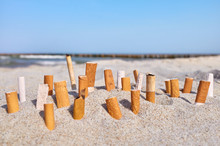 Close Up Picture Of Cigarette Butts Stuck In Sand On A Beach, Selective Focus.