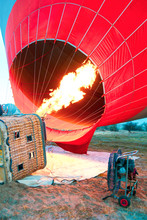 Hot Air Balloon With Flame And Basket Lying On The Ground On The Field While Filling With Air And Preparing To Take Off.