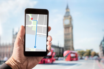 Hand holding smartphone with map on screen in London