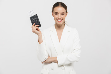 Wall Mural - Beautiful happy woman posing isolated over white wall background holding passport.