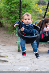 Smiling baby boy on a children swing