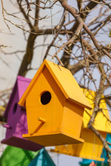 Closeup of yellow birdhouse on tree